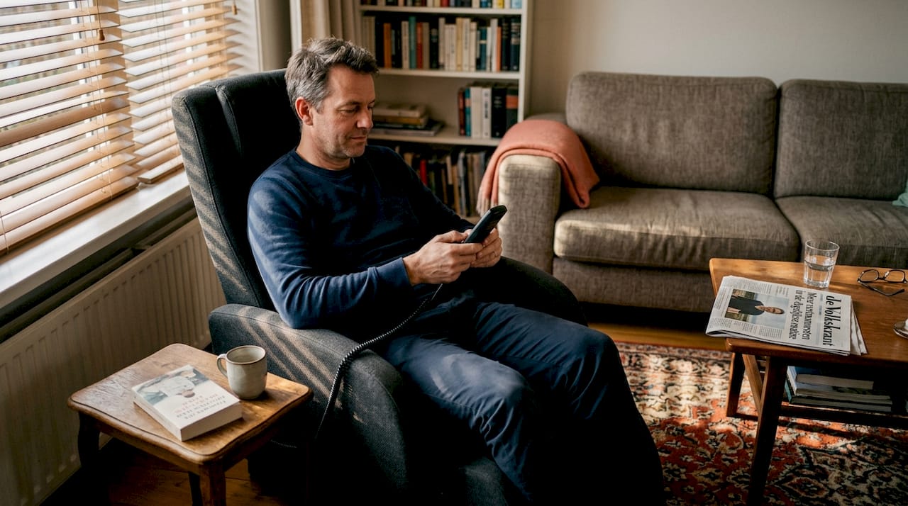 Een man stelt de massagestoel af in zijn sfeervolle woonkamer.